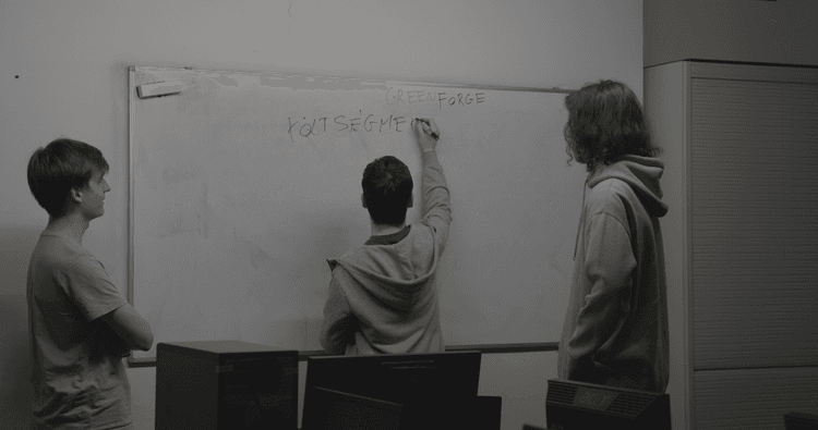 Members of the Greenforge-team are writing on a whiteboard.